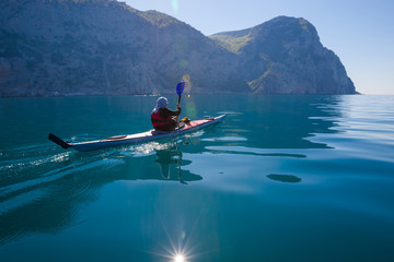 Kayak. People kayaking in sea with calm blue water near mountain
