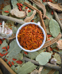 Safflower in the bowl on herbs background