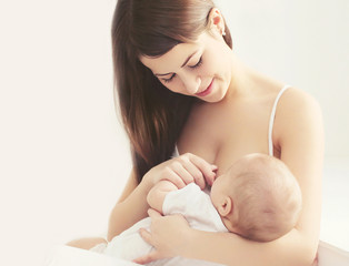 Soft photo young mother feeding breast her baby at home in white