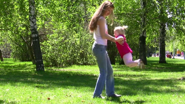 The young woman turns the child in park
