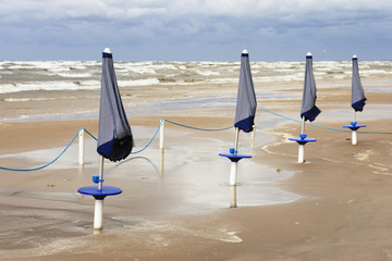 Folded umbrellas on the beach during a storm