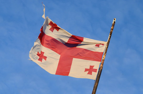 Old georgian national flag with red crosses and the blue sky
