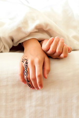 Sleeping little child hands on white bed linen. Indoors closeup.