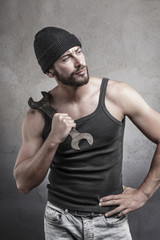 Rough man holding a wrench on his shoulder
