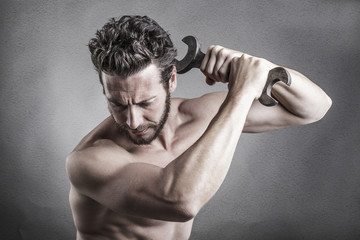bare chest man using a spanner or wrench as a weapon