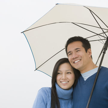 Asian Couple Hugging Under Umbrella