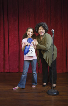 Mixed race girl receiving blue ribbon