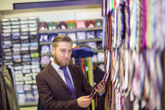 young man chooses a tie, costume shop