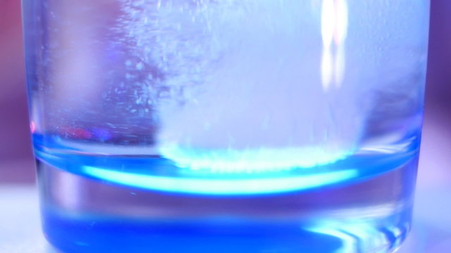 Aspirin tablet drop into glass of water