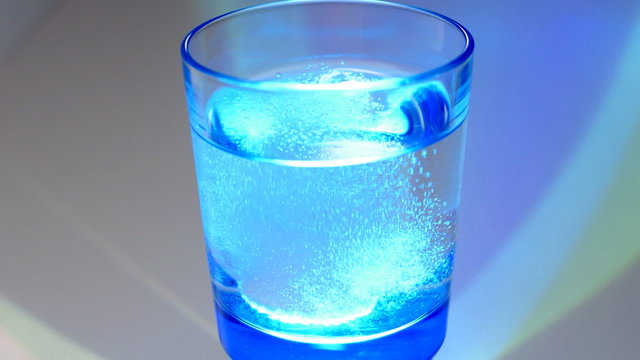 Aspirin tablet drop into glass of water