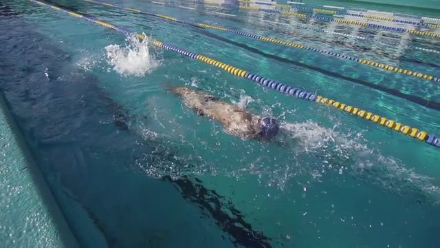 Slow Motion Of Professional Male Swimmer Swimming Backstroke In Lap Pool