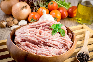 Raw ground meat in wood bowl.