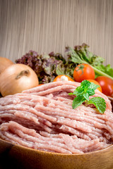 Raw ground meat in wood bowl.
