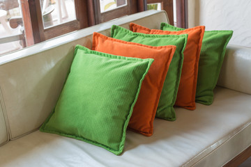 Orange and green Decorative pillows on white leather sofa
