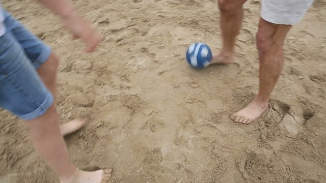 Closeup on feet playing with ball at the beach