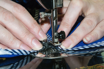 Hands of the seamstress behind work on the sewing machine