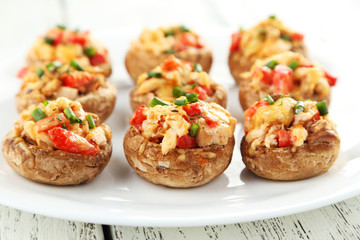 Stuffed mushrooms on plate on white wooden background