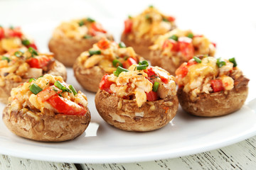 Stuffed mushrooms on plate on white wooden background