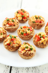 Stuffed mushrooms on plate on white wooden background