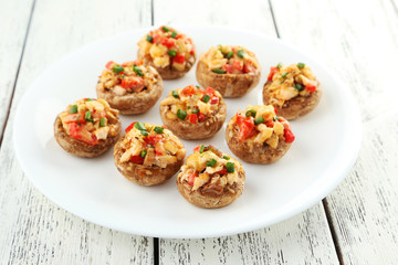 Stuffed mushrooms on plate on white wooden background