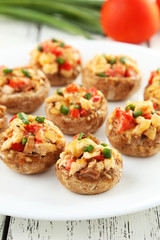 Stuffed mushrooms on plate on white wooden background
