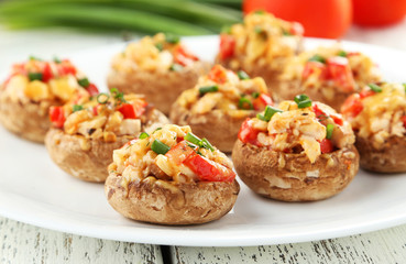 Stuffed mushrooms on plate on white wooden background