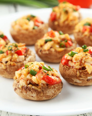Stuffed mushrooms on plate on white wooden background