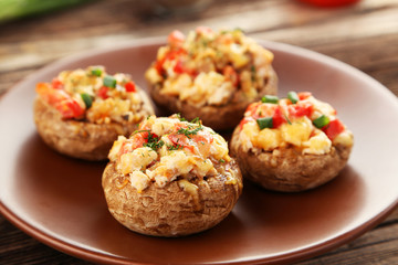 Stuffed mushrooms on plate on brown wooden background