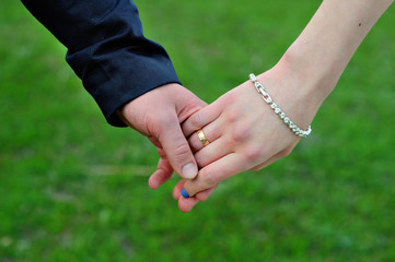 Wedding couple holding hands on grass background