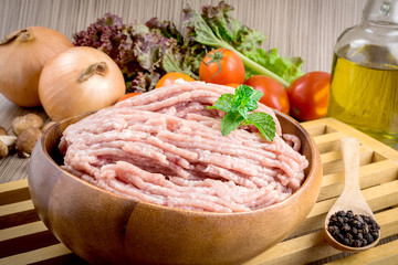 Raw ground meat in wood bowl.