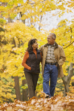 Hispanic Couple Walking In Autumn Leaves