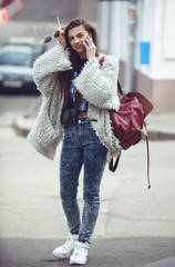 Cheerful woman talking on the phone in the street wearing a gray