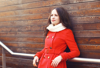 Beautiful woman in red jacket outdoors on against a wooden wall