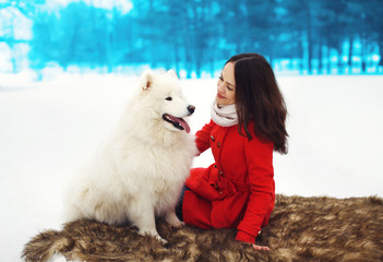 Happy woman owner having fun with white Samoyed dog outdoors in