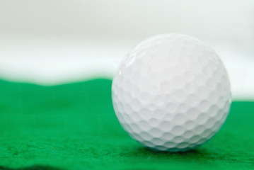 one clean new white golf ball on green artificial turf