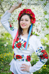 smiling girl in national dress among flowering trees