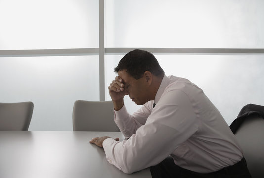 Hispanic businessman with head in hand - Powered by Adobe