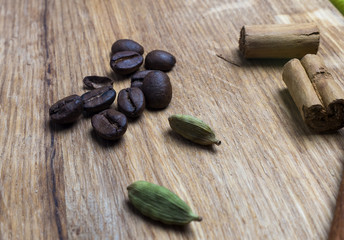 Coffe beans, cardamom and cinamon on wooden desk