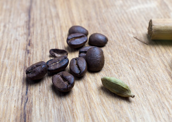 Coffe beans, cardamom and cinamon on wooden desk