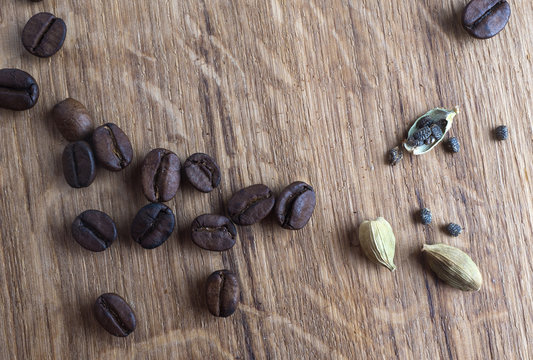 Coffe beans, cardamom and cinamon on wooden desk