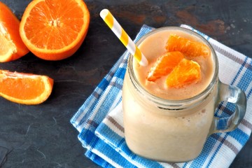 Orange fruit smoothie in a mason jar on checked cloth