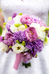 bride holding bridal bouquet with white, pink and purple flowers