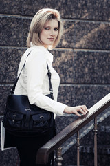 Fototapeta na wymiar Young fashion business woman with handbag at office building