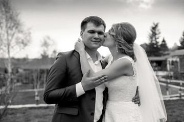 black and white portrait of bride giving a kiss on grooms cheek