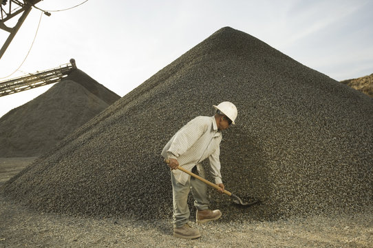 Hispanic man shoveling gravel