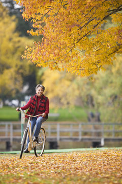 African woman riding bicycle in park in autumn