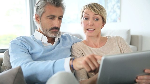 Middle-aged couple websurfing on internet with touchpad, 