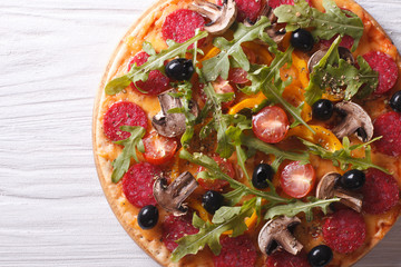 pizza with rocket salad and salami, horizontal top view 
