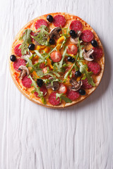 pizza with rocket salad and salami, vertical top view 
