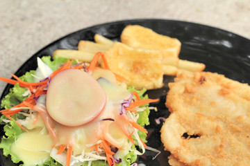 fish steaks and vegetable salad with french fries.